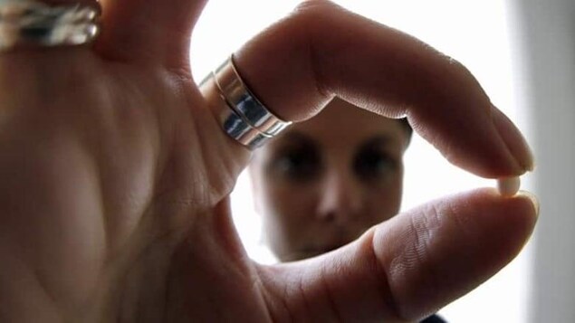 Une main qui prend entre deux doigts une pilule contraceptive

