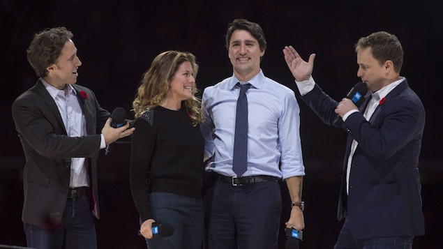 Quatre personnes sur scène lors d'un événement public.