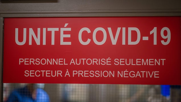 Une affiche sur la porte battante d'un hôpital annonçant Unité COVID-19.