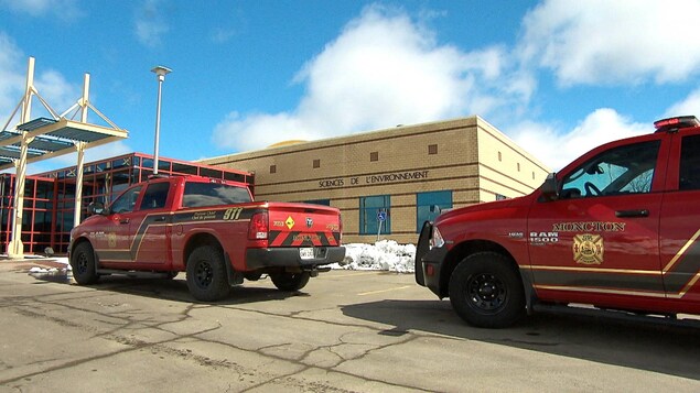 Deux camionnettes rouges des pompiers de Moncton sont immobilisées devant un bâtiment de briques jaune sur lequel les mots « Sciences de l'environnement » sont écrits.
