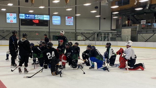 Des joueurs de hockey écoutent les instructions lors d'un entraînement.
