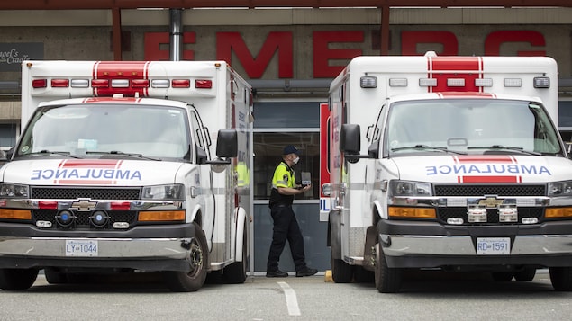 Une personne passe entre deux ambulances garées.