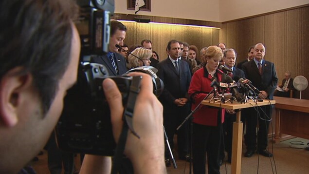 Entourée d'acteurs politiques, Lise Landry prend la parole lors d'une conférence de presse. Entourée d'acteurs politiques, Lise Landry prend la parole lors d'une conférence de presse.