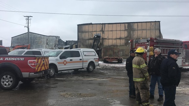 Des véhicules d'urgence et des pompiers devant les ruines de l'usine Des véhicules d'urgence et des pompiers devant les ruines de l'usine