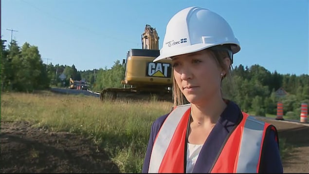 Une dame porte un casque blanc et un dossard sur les lieux d'un chantier de construction. Une dame porte un casque blanc et un dossard sur les lieux d'un chantier de construction.