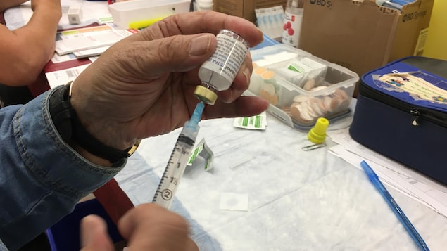 Un préposé prépare une dose de vaccin.