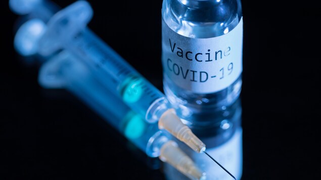 Une seringue et une fiole sur laquelle on peut lire : « Vaccin, COVID-19 ».