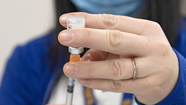 Une infirmière verse du vaccin de la fiole à la seringue.