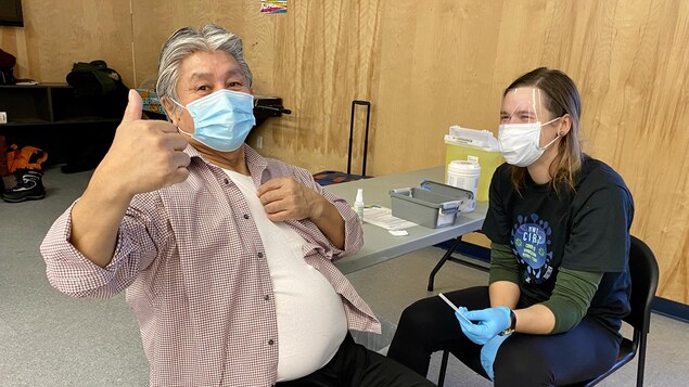 Un homme a un pouce en l'air après avoir reçu son vaccin.