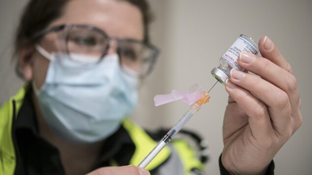 Une ambulancière remplit une seringue d'une dose du vaccin de Moderna.