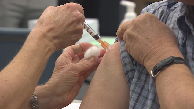 Un patient avec la manche de sa chemise relevée se fait vacciner contre la grippe en Colombie-Britannique.
