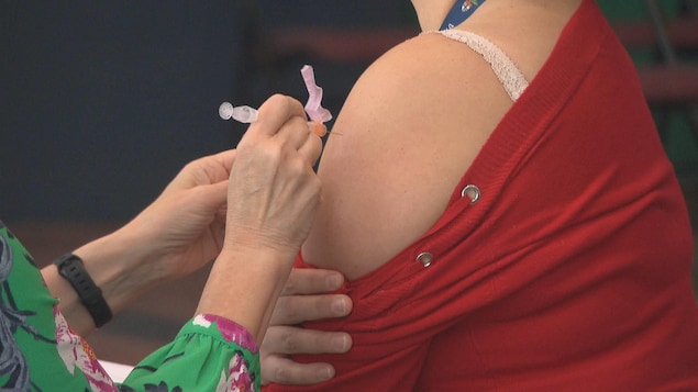 Aiguille dans le bras d'une femme lors d'une vaccination.