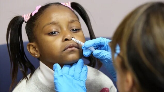 Une petite fille reçoit un vaccin par vaporisateur nasal.