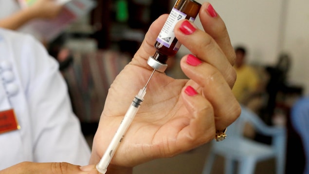 Une infirmière insère une seringue dans une fiole de vaccin contre la rougeole, la rubéole et les oreillons.