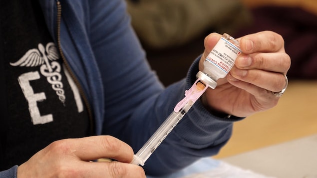 Une aiguille de vaccination perce une fiole du vaccin Moderna.