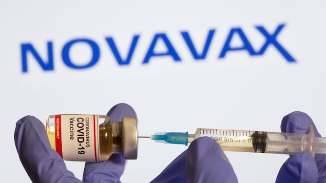 Une fiole du vaccin tenue dans une main gantée avec une seringue. 