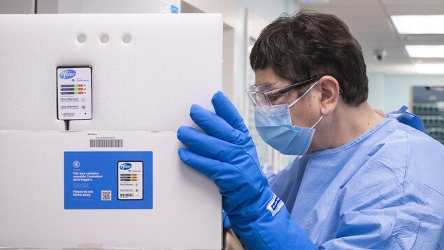 Un travailleur de la santé tient un carton de Pfizer.