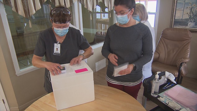 Du personnel de la santé inspecte une boite de vaccins.