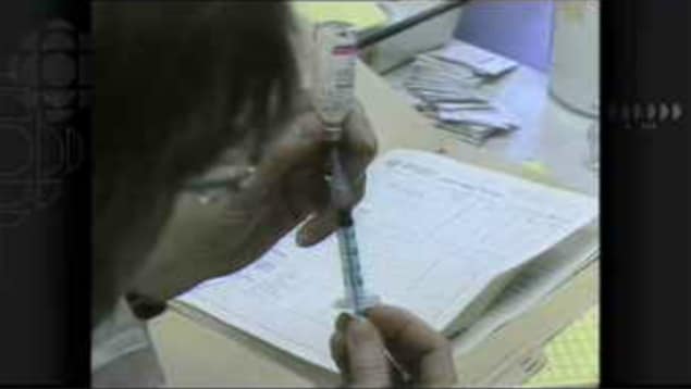 Gros plan des mains d'une infirmière qui remplit une seringue avec un vaccin contre la rougeole.