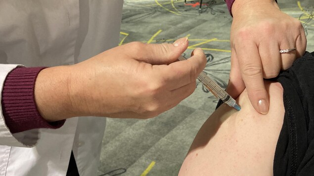 Une femme administre un vaccin.
