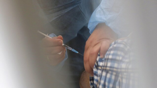 Le bras d'un homme en train de se faire vacciner.