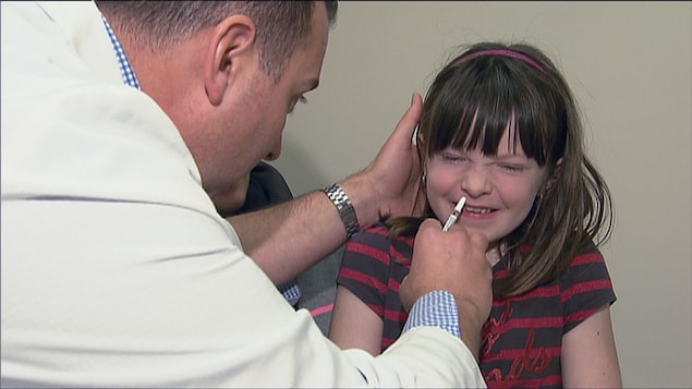 Une fille reçoit un vaccin pour la grippe dans une narine.