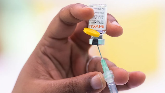Gros plan d'une main qui remplit une seringue de vaccin.