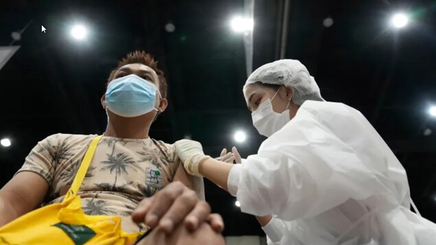Un jeune homme reçoit dans son bras gauche le vaccin contre la COVID-19.