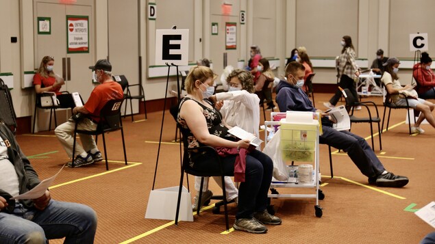 Des personnes reçoivent des vaccins dans une grande salle.