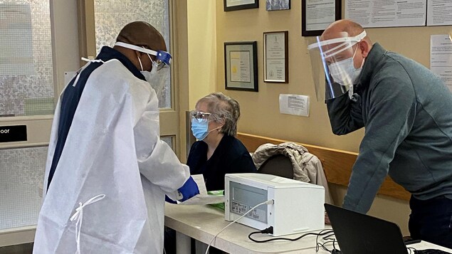 Trois personnes portant le masque près d'ordinateurs.