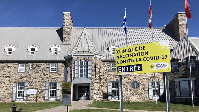 Le Manoir du Saguenay de l'extérieur et une affiche de clinique de vaccination contre la COVID-19.