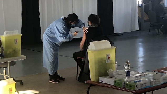 Une infirmière vaccine une femme.