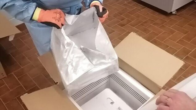 Ouverture d'une boîte de carton remplie de vaccin.