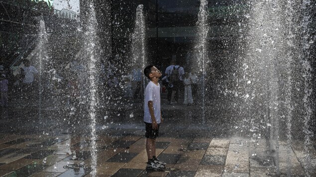 Un garçon se rafraîchit dans une fontaine durant une vague de chaleur à Pékin, en Chine.