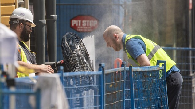 Un travailleur de la construction se rafraîchit devant un ventilateur vaporisateur à Vancouver, le 28 juin 2021.