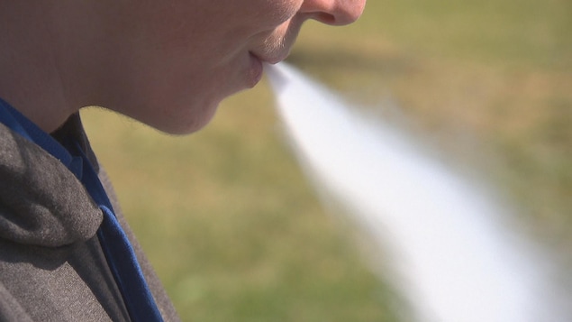 Un adolescent expire une épaisse fumée provenant d'une cigarette électronique qu'il vient de respirer.