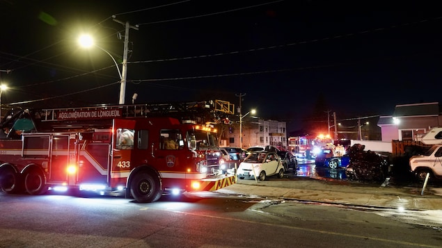 Un véhicule de pompier est sur une scène d'incendie dans le stationnement d'un garage.