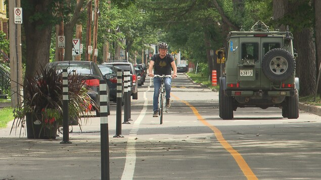 Un homme circule sur une rue alors qu'il y a une piste cyclable.