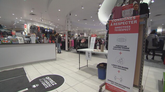 L'entrée d'une boutique de centre commercial avec une pancarte indiquant les mesures sanitaires.