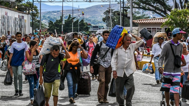 Des gens marchent en traînant des valises.