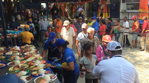 Des migrants vénézuéliens font la queue pour recevoir un repas offert par un organisme caritatif.