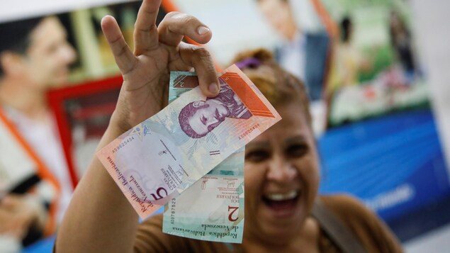 Une femme sourit en brandissant les nouveaux billets de banque du Venezuela. Une femme sourit en brandissant les nouveaux billets de banque du Venezuela.