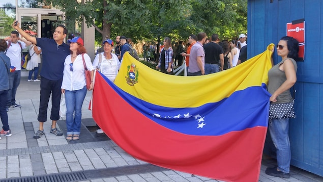 Des Vénézuéliens prennent des photos devant le drapeau de leur pays, à Montréal