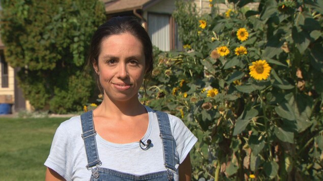 Une jeune femme souriant à la caméra devant des tournesols. Une jeune femme souriant à la caméra devant des tournesols.