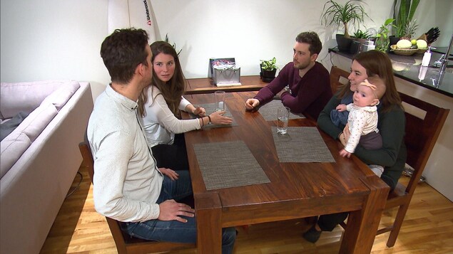 Véronique, sa soeur et leur deux conjoints sont assis autour d'une table de cuisine. Véronique, sa soeur et leur deux conjoints sont assis autour d'une table de cuisine.