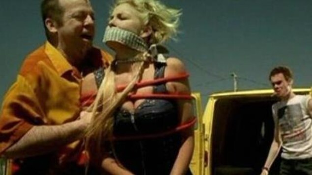 Le comédien Guy Nadon tient Véronique Cloutier, baillonnée et ligotée dans une scène du film. Le comédien Guy Nadon tient Véronique Cloutier, baillonnée et ligotée dans une scène du film.