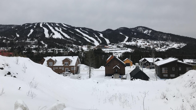 Plusieurs chalets devant un mont de ski.
