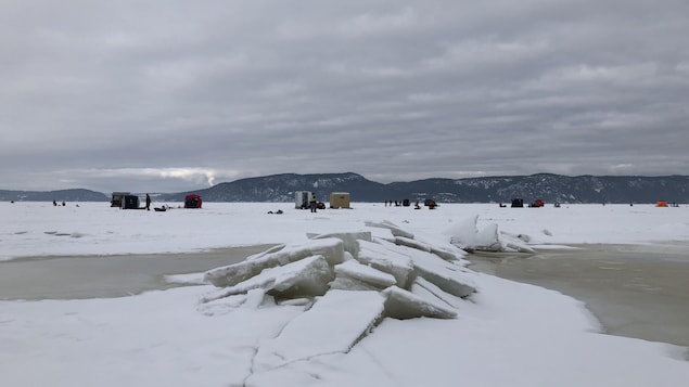 Quelques cabanes mobiles visibles au loin sur la glace.
