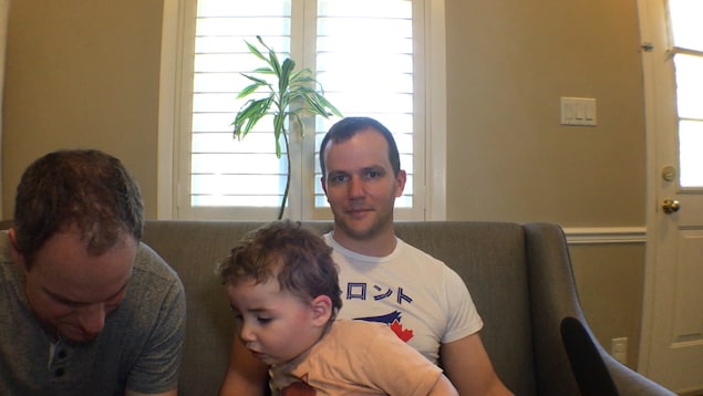 Les 3 personnes sont assises sur le sofa dans le salon.