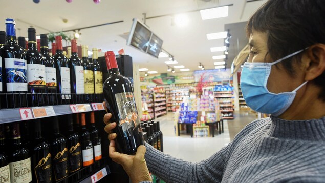 Une femme tient une bouteille de vin.